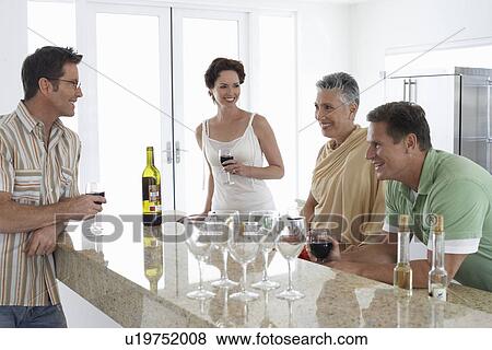 Two couples drinking wine in kitchen View Large Photo Image Stock Photo - Two couples drinking wine in kitchen. Fotosearch