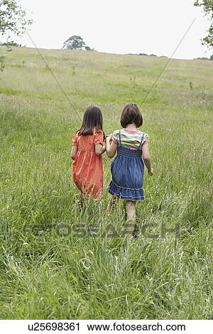Two girls (7-9) holding hands in field View Large Photo Image Stock Image - Two girls (7-9) holding hands in field. Fotosearch