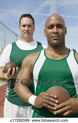 Stock Photo - Two male athletes holding shot and discus, portrait. Fotosearch