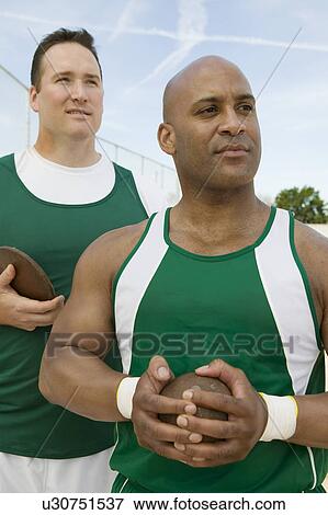 Two male athletes holding shot and discus View Large Photo Image Stock Photo - Two male athletes holding shot and discus. Fotosearch