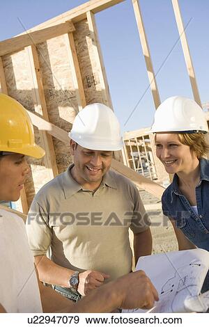 Two men and woman with blueprints at construction site, portrait View Large Photo Image Stock Photo - Two men and woman with blueprints at construction site, portrait. Fotosearch
