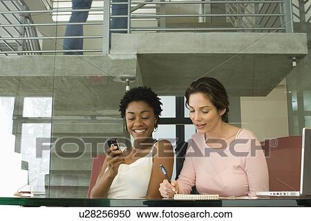 Stock Image - Two mid-adult female office workers having break. Fotosearch