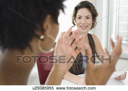 Two mid-adult office workers talking View Large Photo Image Stock Photography - Two mid-adult office workers talking. Fotosearch