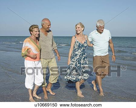 Two senior couples walking barefoot on beach View Large Photo Image Stock Image - Two senior couples walking barefoot on beach. Fotosearch