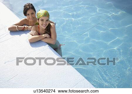Two teenage girls (16-17) in swimming pool, portrait, elevated view View Large Photo Image Picture - Two teenage girls (16-17) in swimming pool, portrait, elevated view. Fotosearch