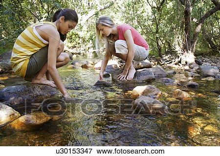 Two teenage girls (16-17 years) squatting on stone by stream in forest, hands in water View Large Photo Image Stock Photo - Two teenage girls (16-17 years) squatting on stone by stream in forest, hands in water. Fotosearch
