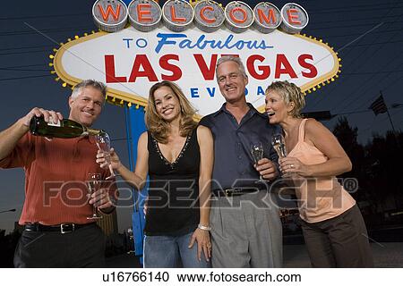 Two women and two men posing in front of Welcome to Las Vegas sign View Large Photo Image Stock Image - Two women and two men posing in front of Welcome to Las Vegas sign. Fotosearch