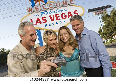 Two women and two men posing in front of Welcome to Las Vegas sign View Large Photo Image Stock Photo - Two women and two men posing in front of Welcome to Las Vegas sign. Fotosearch