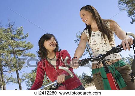 Two women stand smiling with mountain bikes View Large Photo Image Stock Image - Two women stand smiling with mountain bikes. Fotosearch