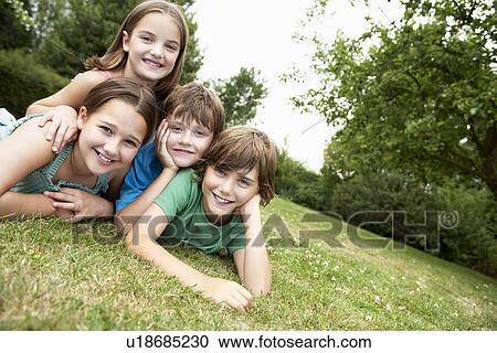 Two young girls and boys lying in park together, portrait View Large Photo Image Stock Image - Two young girls and boys lying in park together, portrait. Fotosearch