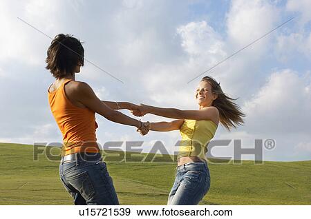 Two young swinging each other around in mountain field, side view View Large Photo Image Stock Photo - Two young swinging each other around in mountain field, side view. Fotosearch
