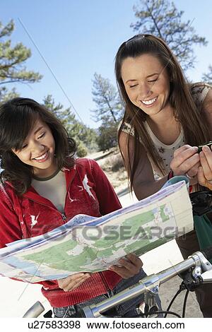Two young women standing with mountain bikes, reading map. View Large Photo Image Stock Photo - Two young women standing with mountain bikes, reading map.. Fotosearch