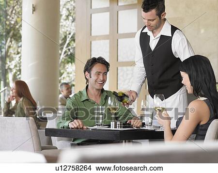 Waiter pouring wine for couple at outdoor restaurant View Large Photo Image Picture - Waiter pouring wine for couple at outdoor restaurant. Fotosearch