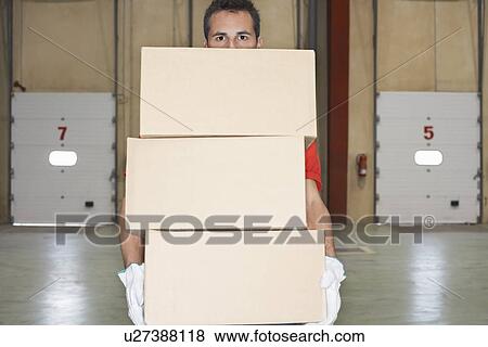Warehouse Worker wearing gloves Carrying Boxes near loading dock doors View Large Photo Image Stock Photo - Warehouse Worker wearing gloves Carrying Boxes near loading dock doors. Fotosearch