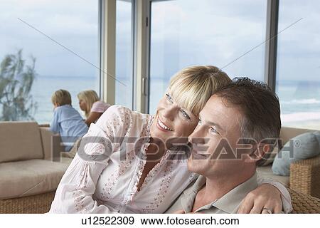 Wife sitting on husband's lap, arms around, on vacation near seaside with children View Large Photo Image Stock Photo - Wife sitting on husband's lap, arms around, on vacation near seaside with children. Fotosearch