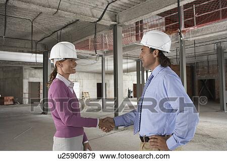 Stock Photo - Woman and man shaking hands at construction site. Fotosearch