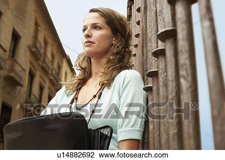 Woman holding briefcase, leaning against railing, low angle view. View Large Photo Image Stock Image - Woman holding briefcase, leaning against railing, low angle view.. Fotosearch