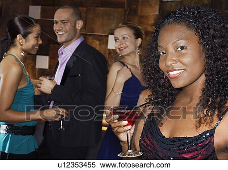 Stock Photography - Woman holding cocktail, standing in bar, portrait. Fotosearch