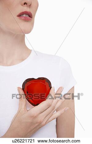 Woman holding heart-shaped jewel between finger and thumb View Large Photo Image Stock Image - Woman holding heart-shaped jewel between finger and thumb. Fotosearch