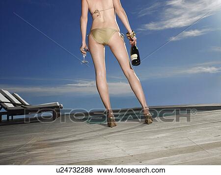 Woman in bikini holding champagne by pool side, back view, low section View Large Photo Image Stock Photo - Woman in bikini holding champagne by pool side, back view, low section. Fotosearch