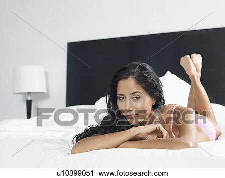 Stock Image - Woman in underwear reclining on bed. Fotosearch