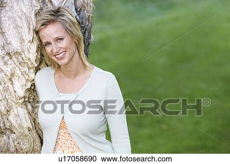 Woman leaning against tree, portrait View Large Photo Image Stock Image - Woman leaning against tree, portrait. Fotosearch