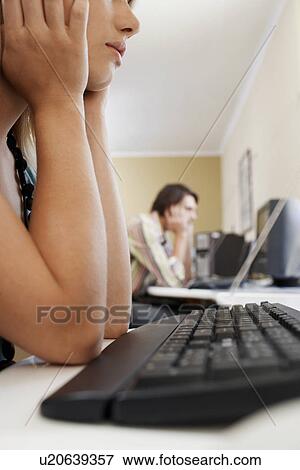 Stock Photo - Woman leaning on elbows in front of computer keyboard, side view.. Fotosearch