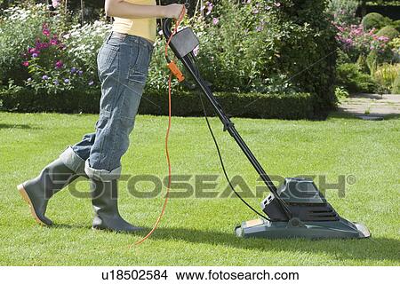 Picture - Woman Mowing Lawn With electric Lawn Mower. Fotosearch