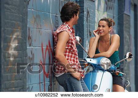 Woman on moped talking to man in street View Large Photo Image Stock Image - Woman on moped talking to man in street. Fotosearch
