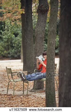 Woman reading book, sitting on chairs in park View Large Photo Image Stock Photo - Woman reading book, sitting on chairs in park. Fotosearch