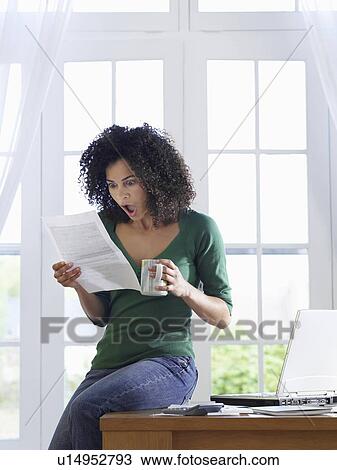 Woman reading paper document, sitting on desk View Large Photo Image Stock Image - Woman reading paper document, sitting on desk. Fotosearch