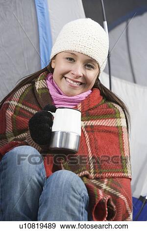 Woman sits in blanket holding cup outside tent View Large Photo Image Stock Photo - Woman sits in blanket holding cup outside tent. Fotosearch
