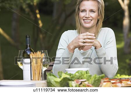 Woman sitting at outdoor table, portrait View Large Photo Image Picture - Woman sitting at outdoor table, portrait. Fotosearch