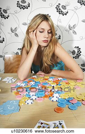 Stock Photograph - Woman Sitting at Table with Chips and Playing Cards. Fotosearch