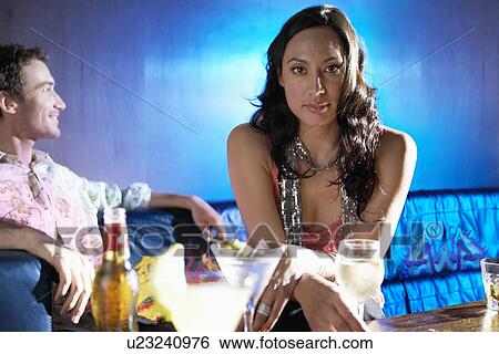 Stock Photograph - Woman sitting in bar, holding wineglass, leaning forward, portrait. Fotosearch