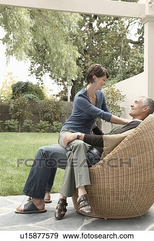 Woman sitting on husband's laps on patio View Large Photo Image Stock Photo - Woman sitting on husband's laps on patio. Fotosearch