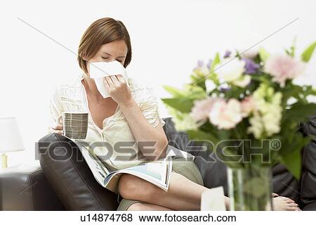 Woman sitting on sofa blowing nose View Large Photo Image Stock Photo - Woman sitting on sofa blowing nose. Fotosearch