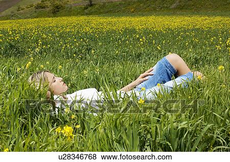 Stock Photo - Woman sleeping in flowery meadow, side view. Fotosearch