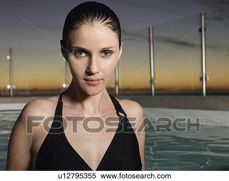 Stock Photography - Woman standing in outdoor pool at sunset. Fotosearch