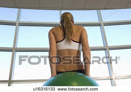 Stock Image - Woman Using Exercise Ball in Gym. Fotosearch