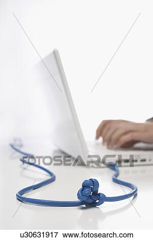 Woman using lap top with knotted cable in studio, close up on knot View Large Photo Image Stock Photo - Woman using lap top with knotted cable in studio, close up on knot. Fotosearch