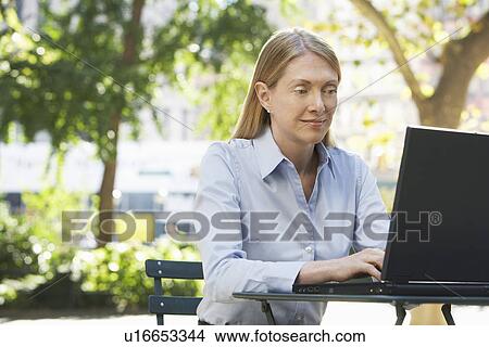 Picture - Woman using laptop outdoors. Fotosearch