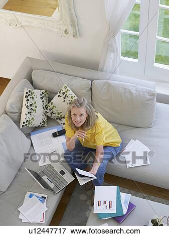Stock Photo - Woman using laptop sitting on sofa, elevated view. Fotosearch