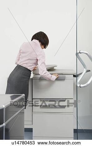 Stock Image - Woman using photocopier in office. Fotosearch