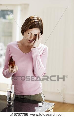 Woman with headache holding pills, touching head View Large Photo Image Stock Photograph - Woman with headache holding pills, touching head. Fotosearch