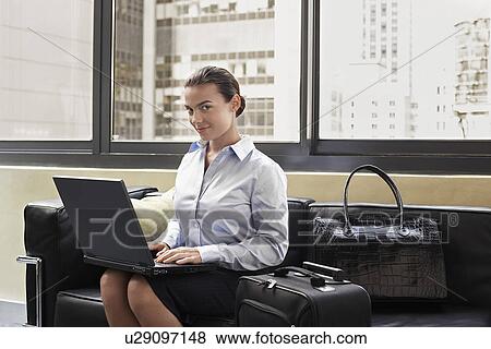 Woman with luggage using laptop, sitting on sofa View Large Photo Image Stock Photo - Woman with luggage using laptop, sitting on sofa. Fotosearch