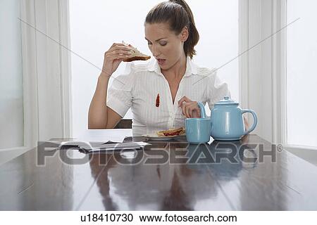 Stock Image - Woman with stain on blouse at dining room table. Fotosearch