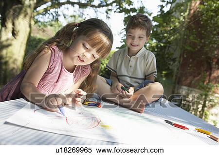 Stock Photography - Young boy and girl drawing on table in back garden. Fotosearch