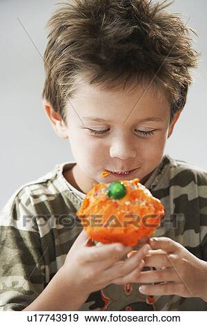 Young boy eating cupcake, half length View Large Photo Image Stock Photo - Young boy eating cupcake, half length. Fotosearch