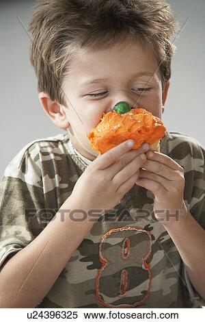 Young boy eating cupcake, half length View Large Photo Image Stock Photography - Young boy eating cupcake, half length. Fotosearch